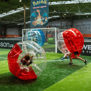 Enfant qui courent et roulent dans des bulles gonflables sur un terrain synthétique